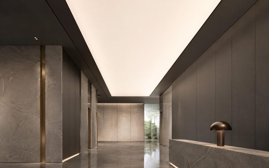 Backlit luminous stretch ceiling lighting a stone lobby with a travertine reception desk
