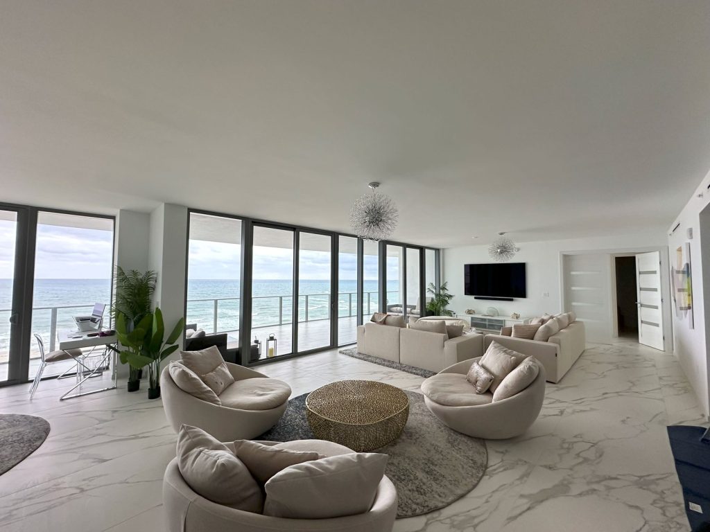 Oceanfront condo living room with a flat white ceiling and two small pendant fixtures, before